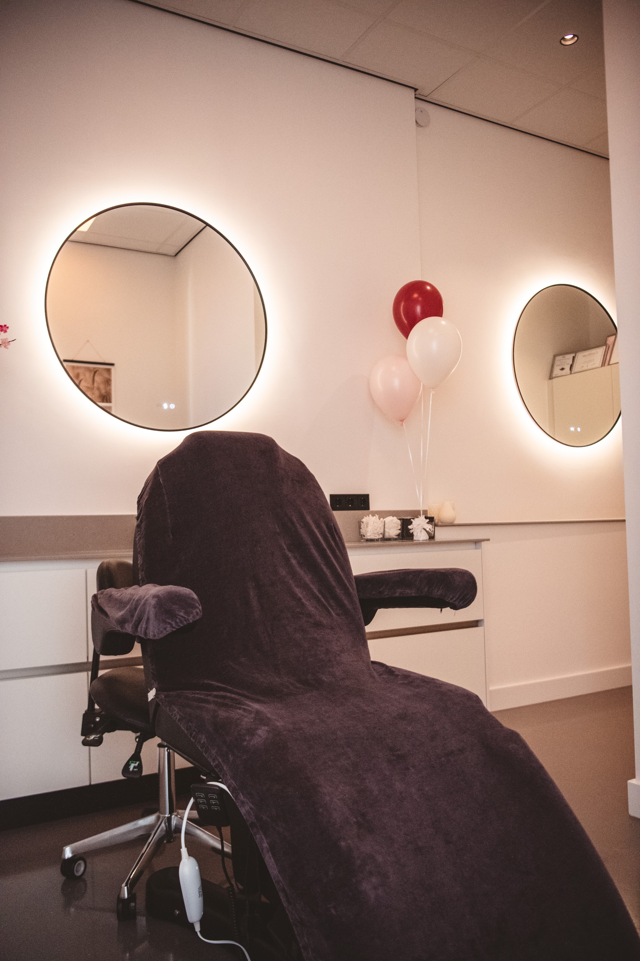 De behandelkamer met behandelstoel en verlichte ronde spiegels