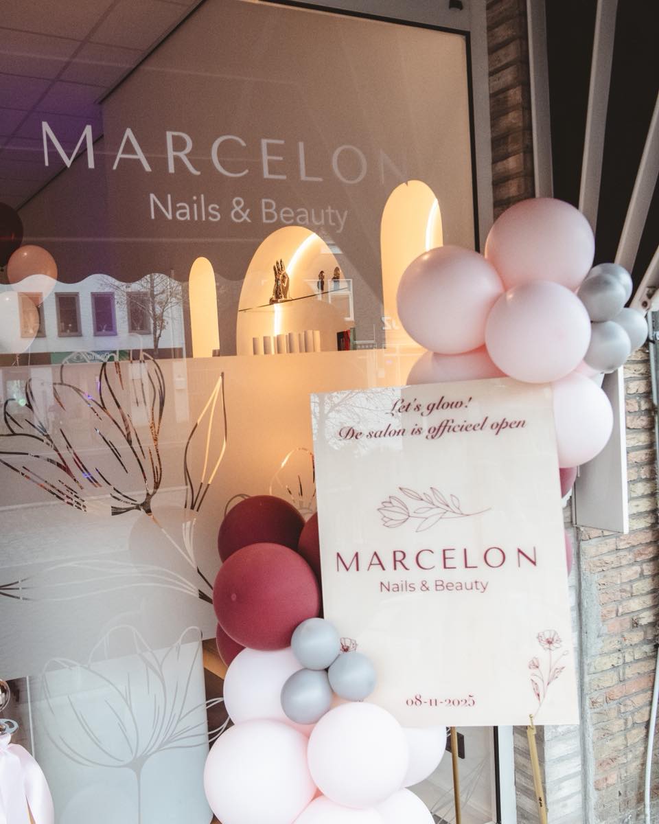 Het raam van de salon op de openingsdag met ballonnen en het bord 'De salon is officieel open'